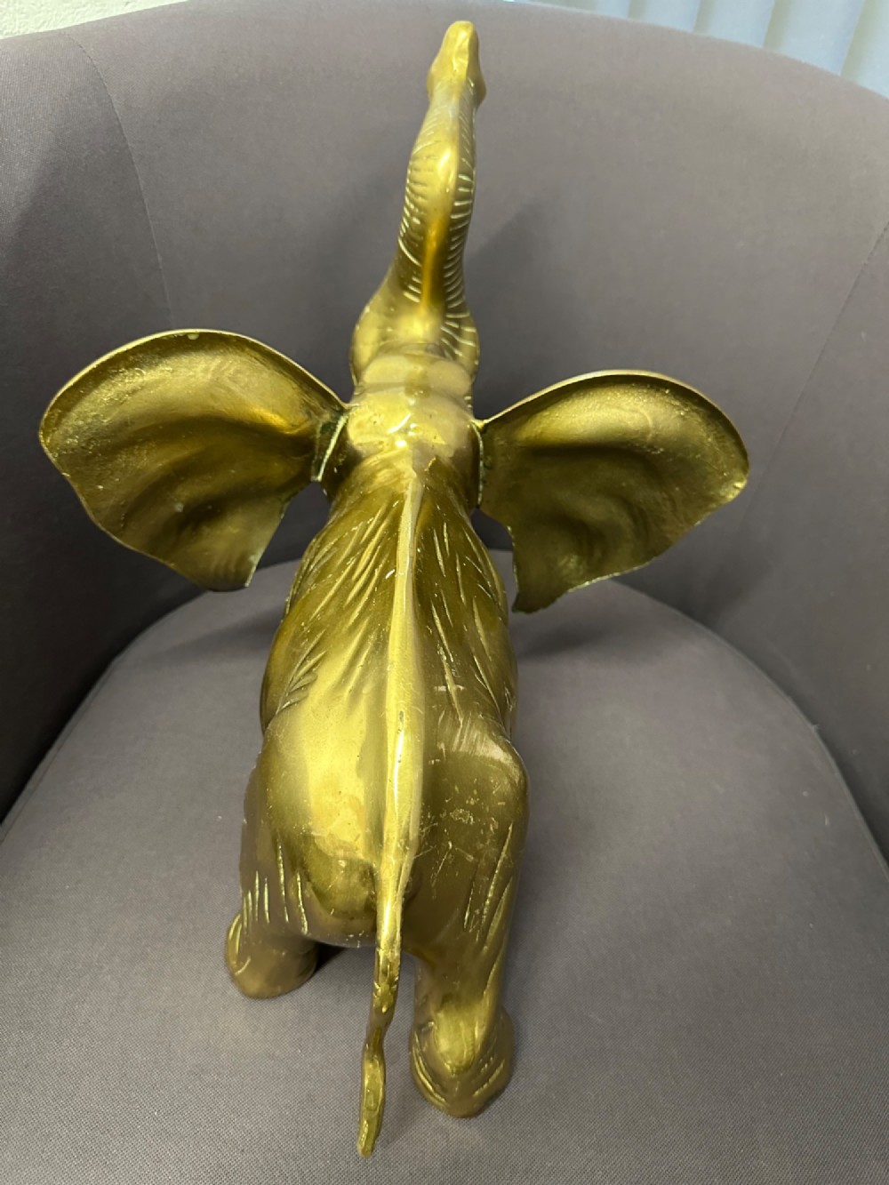 A solid brass sculpture of an elephant standing with its trunk raised up. View VI
