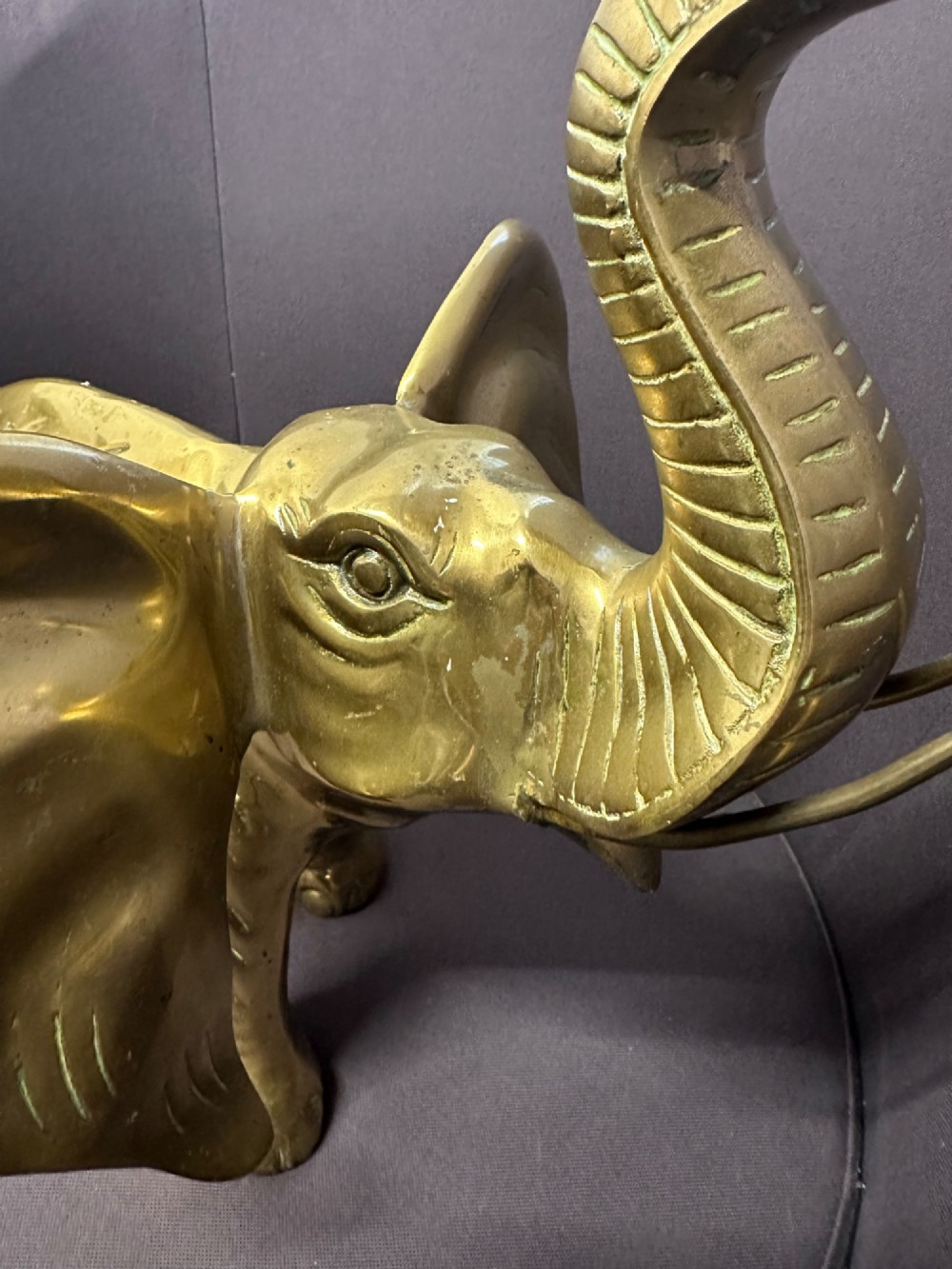 A solid brass sculpture of an elephant standing with its trunk raised up. View X