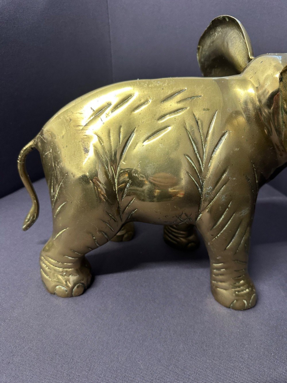 A solid brass sculpture of an elephant standing with its trunk raised up. View XI
