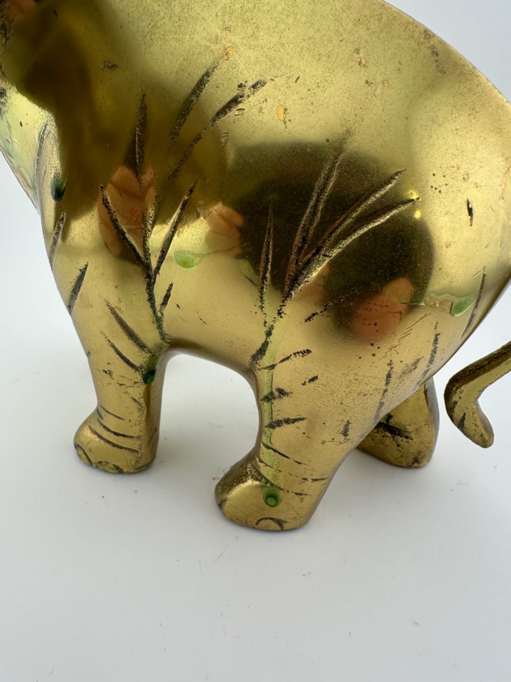 A solid cast brass elephant sculpture with an elevated raised trunk, detailed engraving along the body, and a polished gold finish. View VIII
