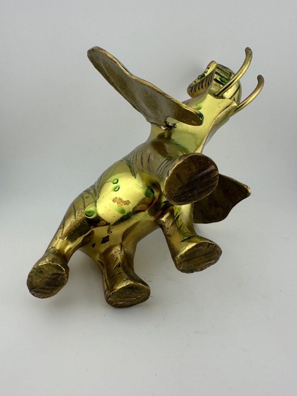 A solid cast brass elephant sculpture with an elevated raised trunk, detailed engraving along the body, and a polished gold finish. View XI