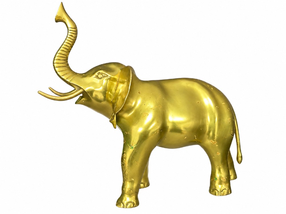 A vintage cast brass elephant sculpture standing with its trunk raised high.