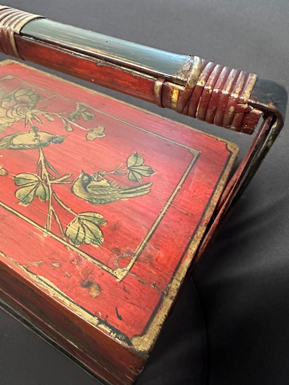 A three-tiered Chinese red lacquer wedding basket featuring hand-painted gold floral motifs and a black wooden carrying handle. View II