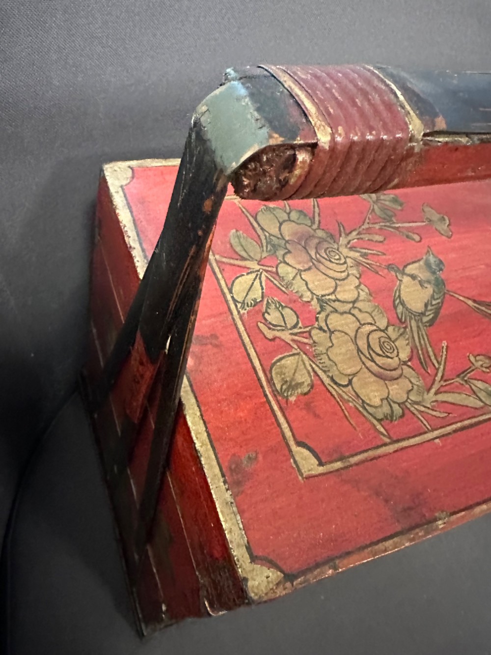 A three-tiered Chinese red lacquer wedding basket featuring hand-painted gold floral motifs and a black wooden carrying handle. View III