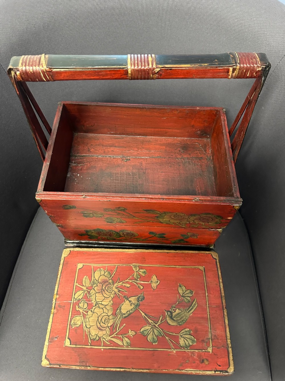A three-tiered Chinese red lacquer wedding basket featuring hand-painted gold floral motifs and a black wooden carrying handle. View VIII