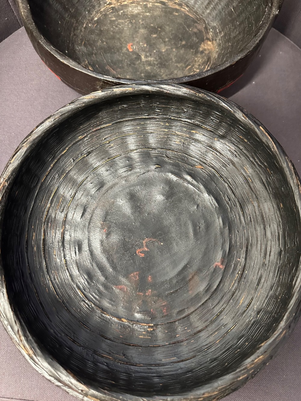 A traditional Chinese red and black lacquered rice basket featuring a high arched handle and painted decorative motifs on the lid. View VI
