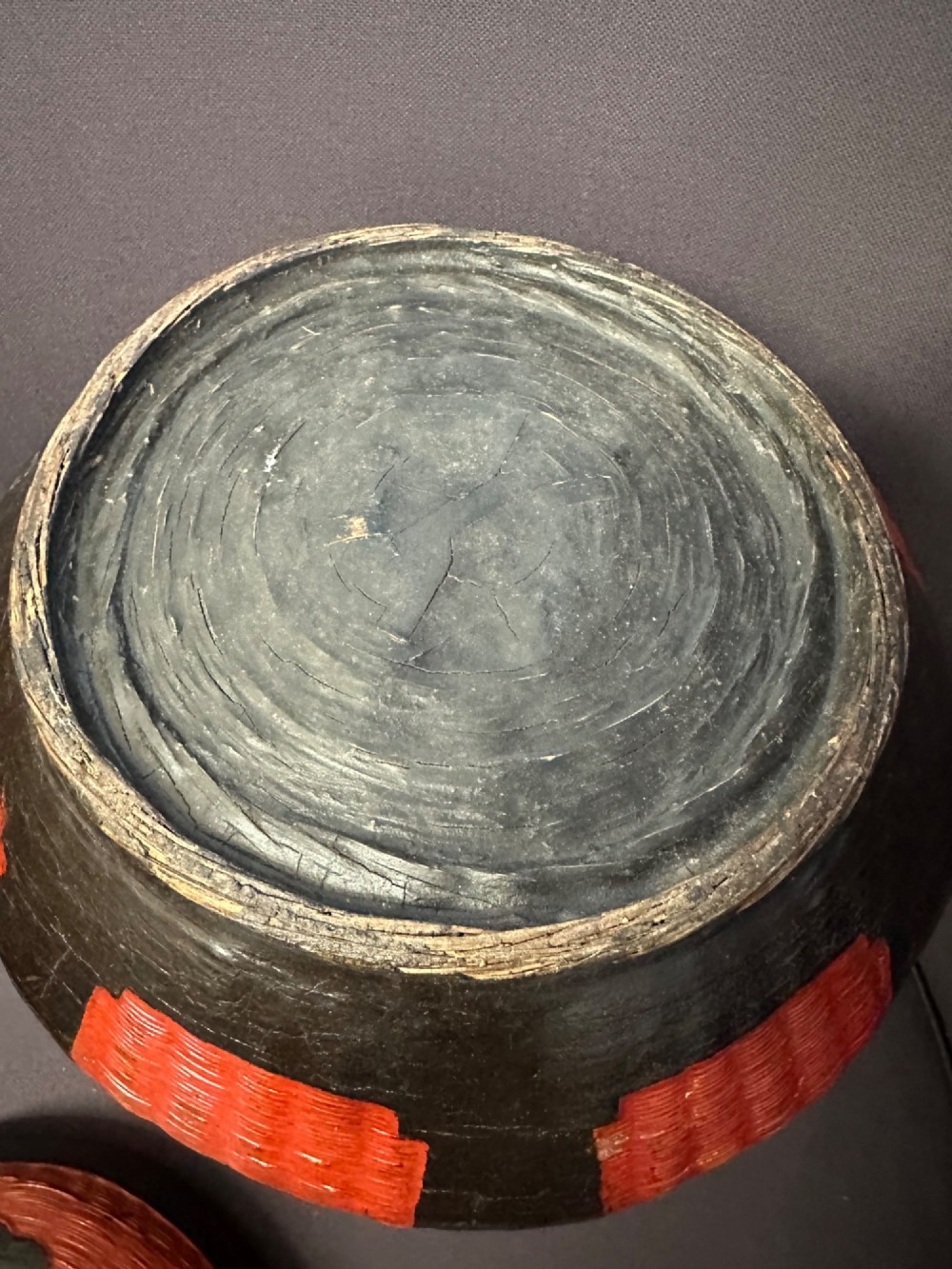 A traditional Chinese red and black lacquered rice basket featuring a high arched handle and painted decorative motifs on the lid. View VII