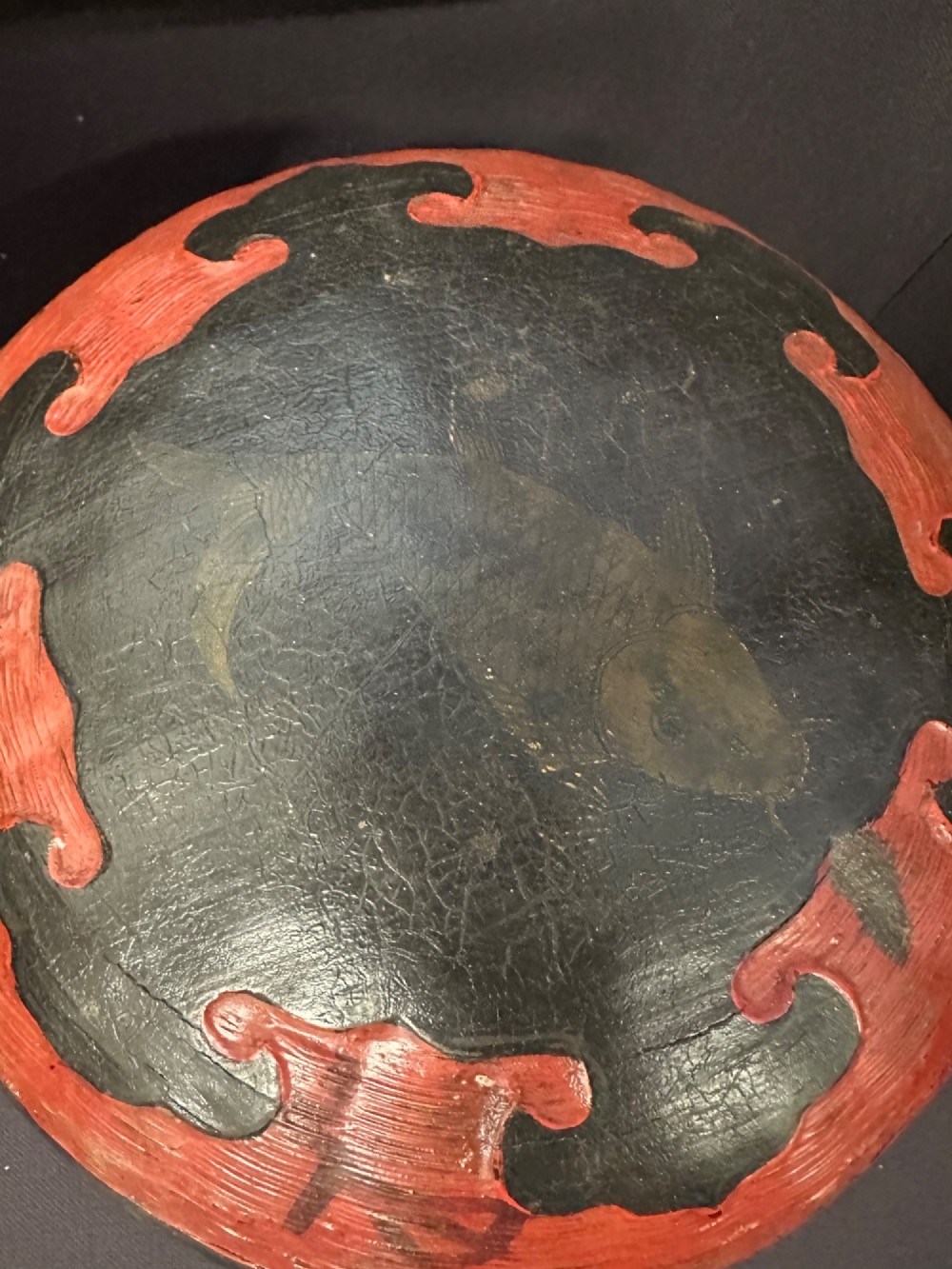 A traditional Chinese red and black lacquered rice basket featuring a high arched handle and painted decorative motifs on the lid. View X