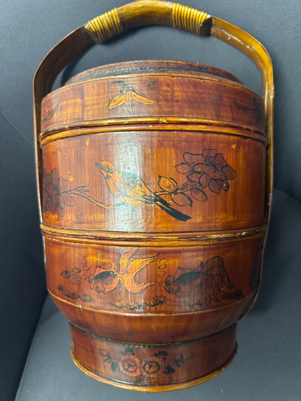 A late Qing Dynasty tiered Chinese food basket crafted from warm amber bamboo and wood, hand-painted with black line illustrations of a child on the lid and floral motifs around the body. View IV