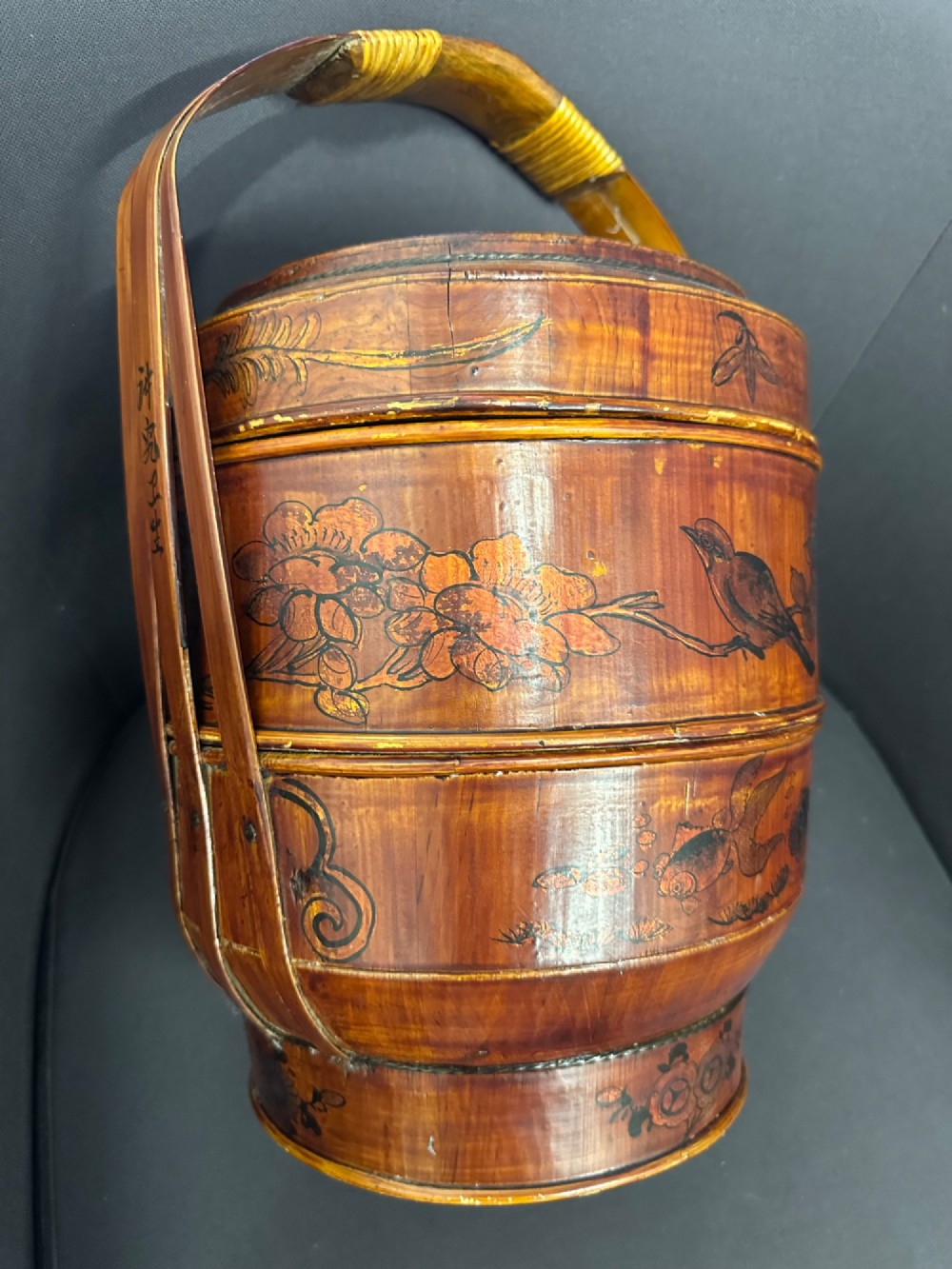 A late Qing Dynasty tiered Chinese food basket crafted from warm amber bamboo and wood, hand-painted with black line illustrations of a child on the lid and floral motifs around the body. View VI