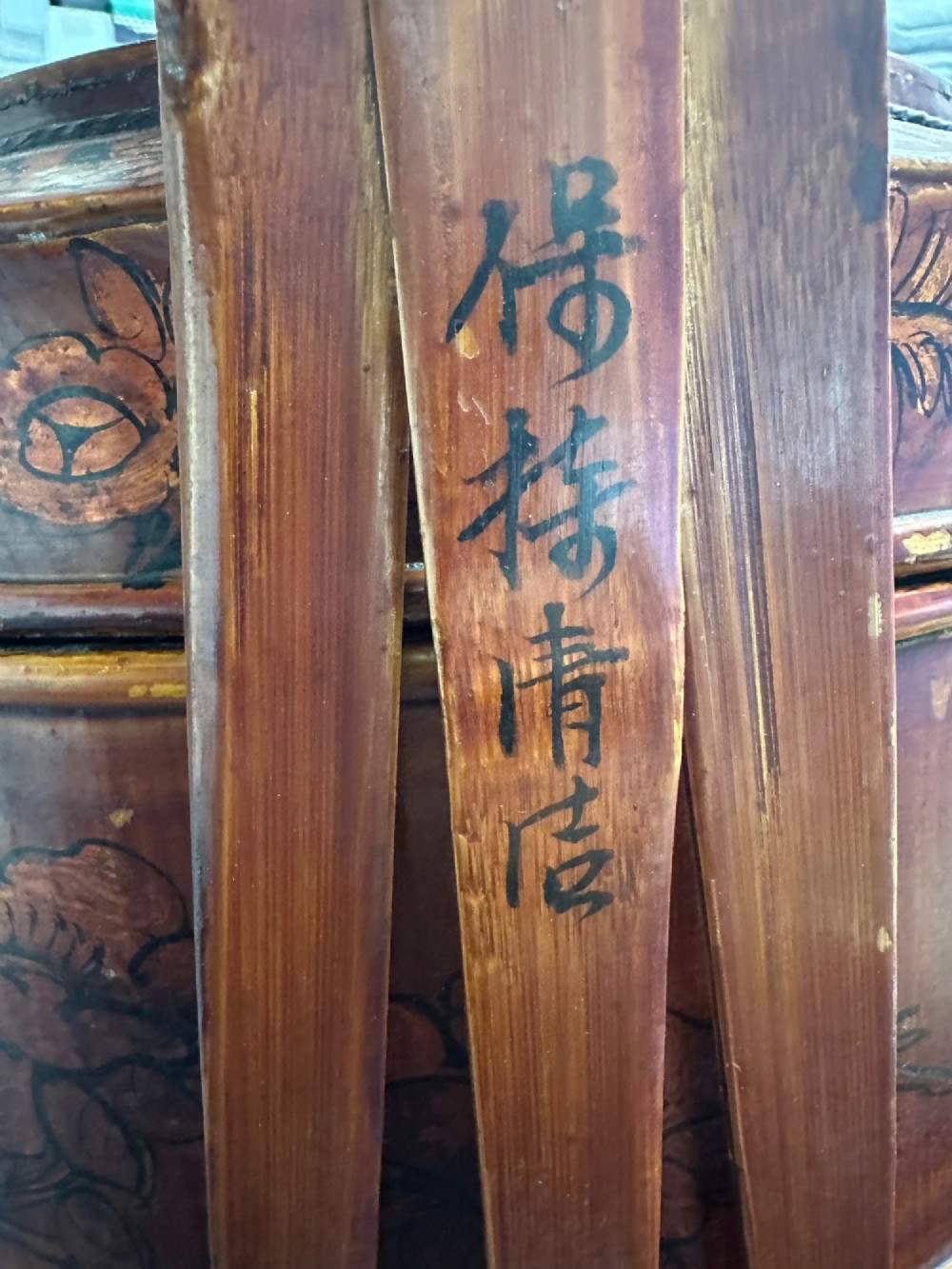A late Qing Dynasty tiered Chinese food basket crafted from warm amber bamboo and wood, hand-painted with black line illustrations of a child on the lid and floral motifs around the body. View XII