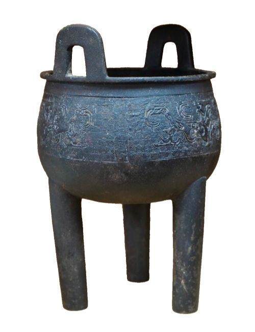 A dark patinated bronze tripod censer featuring upright loop handles and relief taotie mask carvings around the vessel body. View III