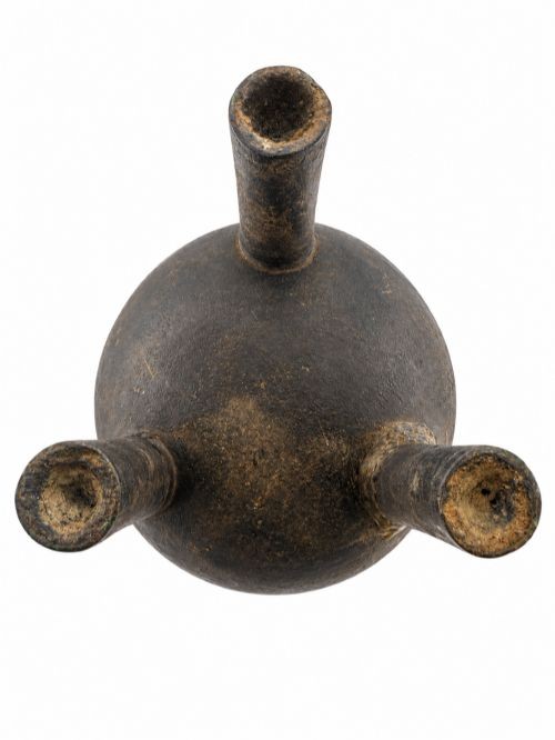 A dark patinated bronze tripod censer featuring upright loop handles and relief taotie mask carvings around the vessel body. View V
