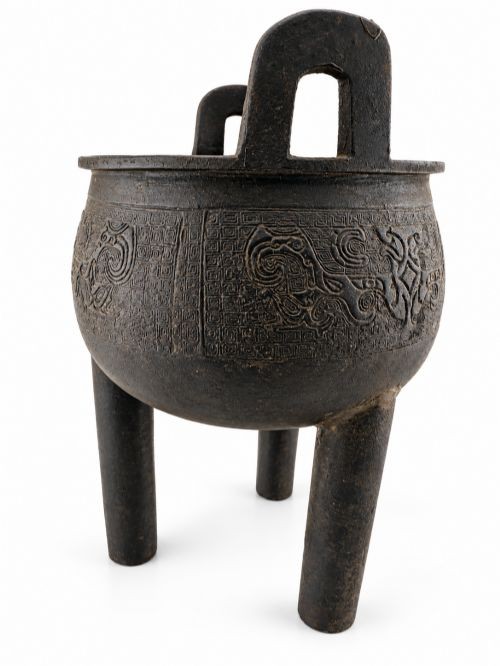 A dark patinated bronze tripod censer featuring upright loop handles and relief taotie mask carvings around the vessel body. View VIII
