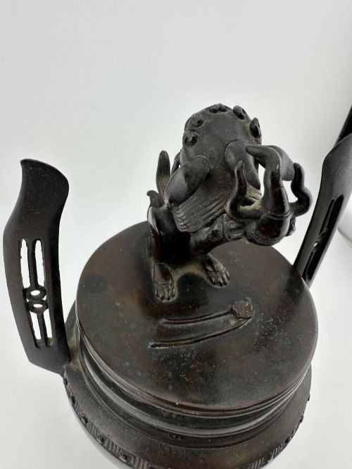 A dark patinated bronze tripod censer with a lid surmounted by a Qilin finial and featuring two tall pierced handles. View III