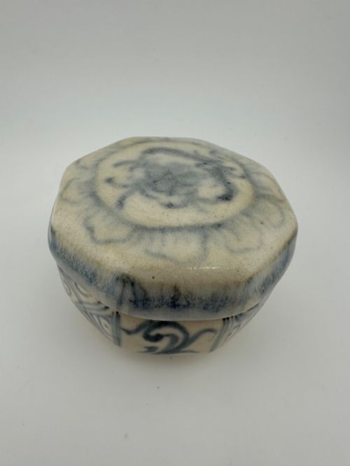 An antique octagonal ceramic lidded box featuring cobalt blue hand-painted scrolling motifs against an off-white glaze. View XI