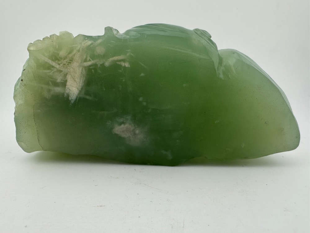 A hand-carved light green jadeite sculpture depicting a seated Laughing Buddha resting on a dark wooden fitted base. View VIII