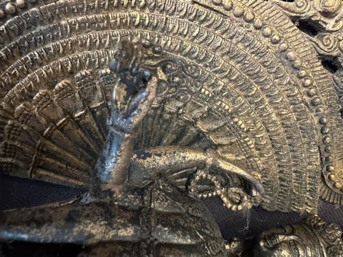A dark bronze Tibetan sculpture depicting the eleven-headed deity Avalokiteshvara standing on a tiered lotus pedestal against an ornate halo. View XIV
