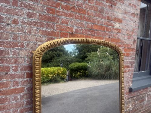 A large 19th-century overmantel mirror featuring an arched gold giltwood frame with fluted moulding detailing and a flat base. View II