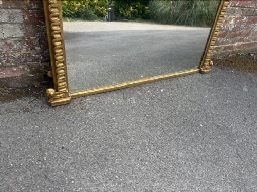 A large 19th-century overmantel mirror featuring an arched gold giltwood frame with fluted moulding detailing and a flat base. View V