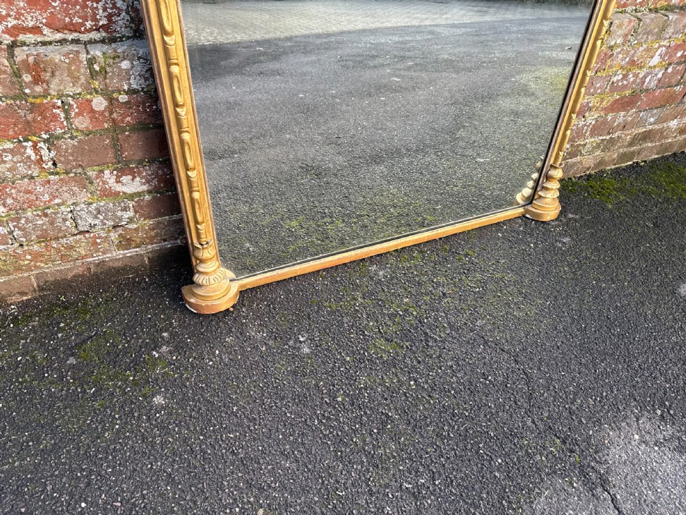 A large 19th-century giltwood overmantel mirror featuring an arched top frame decorated with beaded moulding and pilaster side columns. View V