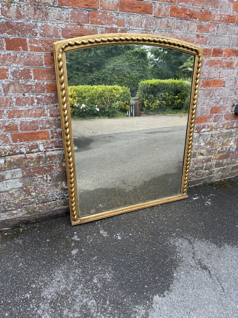 A large 19th-century Victorian overmantel mirror featuring a gently arched top and a carved beaded giltwood frame.
