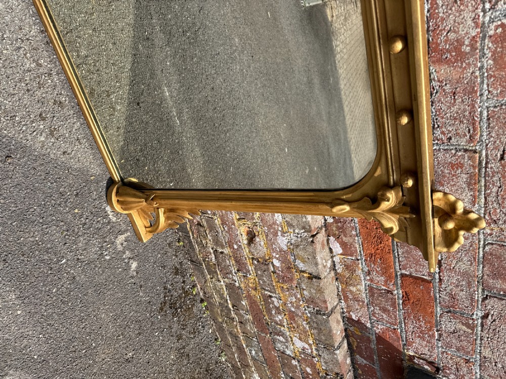 A 19th-century English giltwood and gesso overmantel mirror featuring detailed acanthus leaf carving and ball moulding along the upper frame. View III