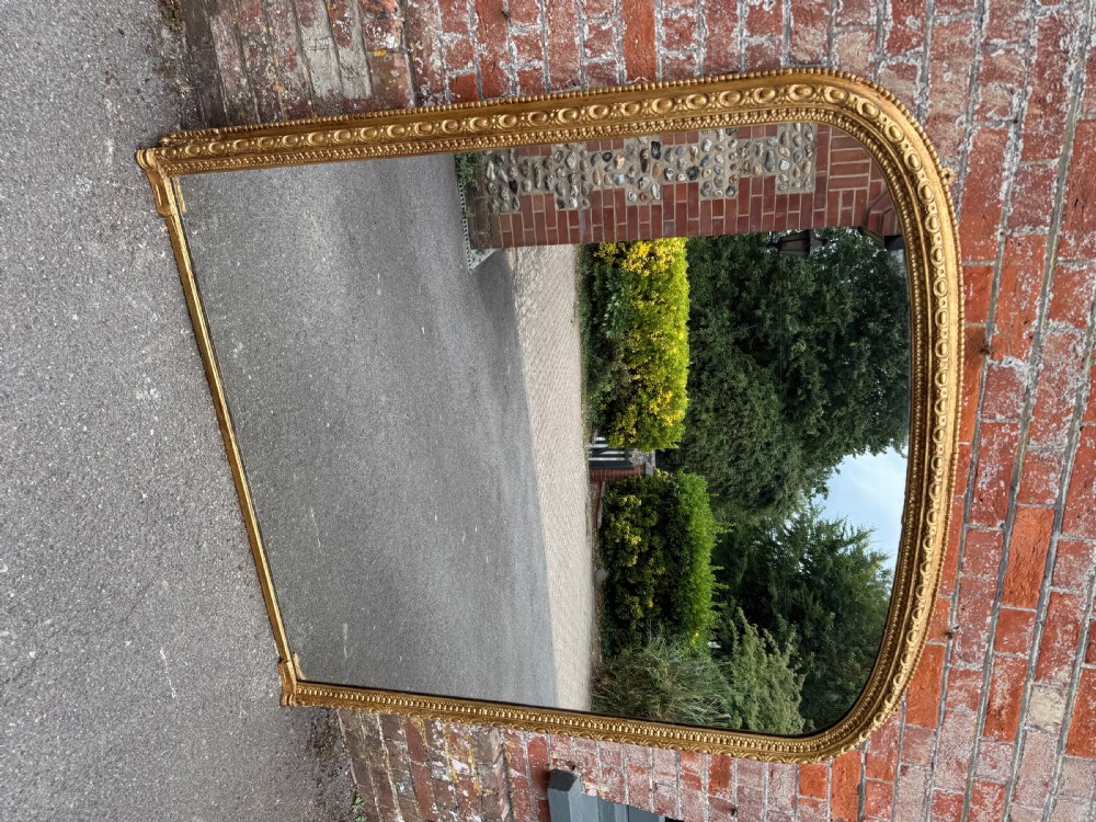 A large 19th-century Victorian arched overmantel mirror with a gilded wood and gesso frame featuring beaded moulding. View VII