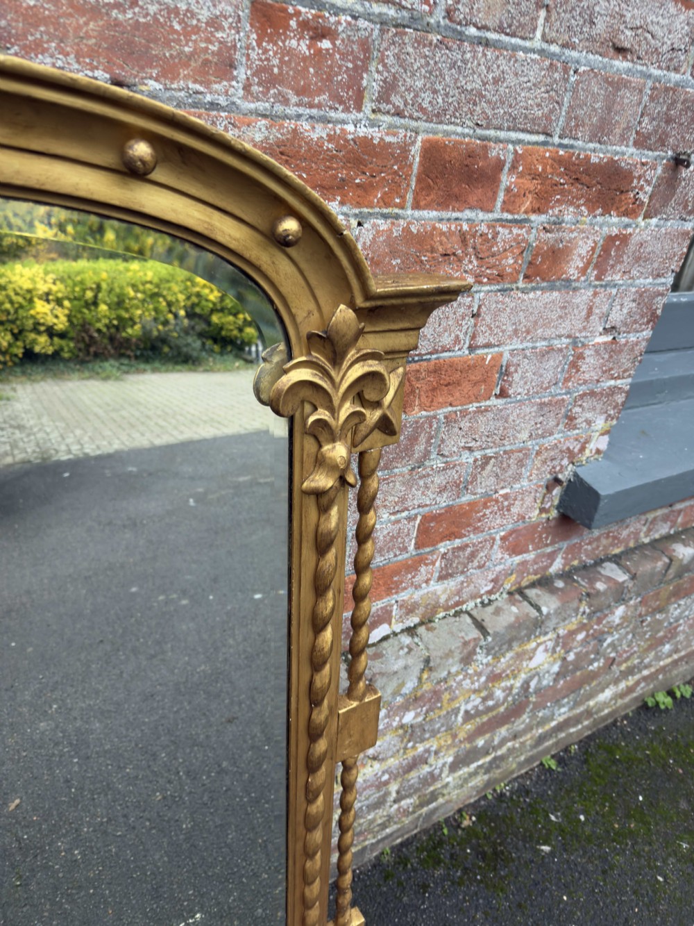 An English nineteenth-century giltwood overmantel mirror featuring an arched top decorated with rounded studs and flanked by carved spiral-twist columns with acanthus leaf motifs. View VI