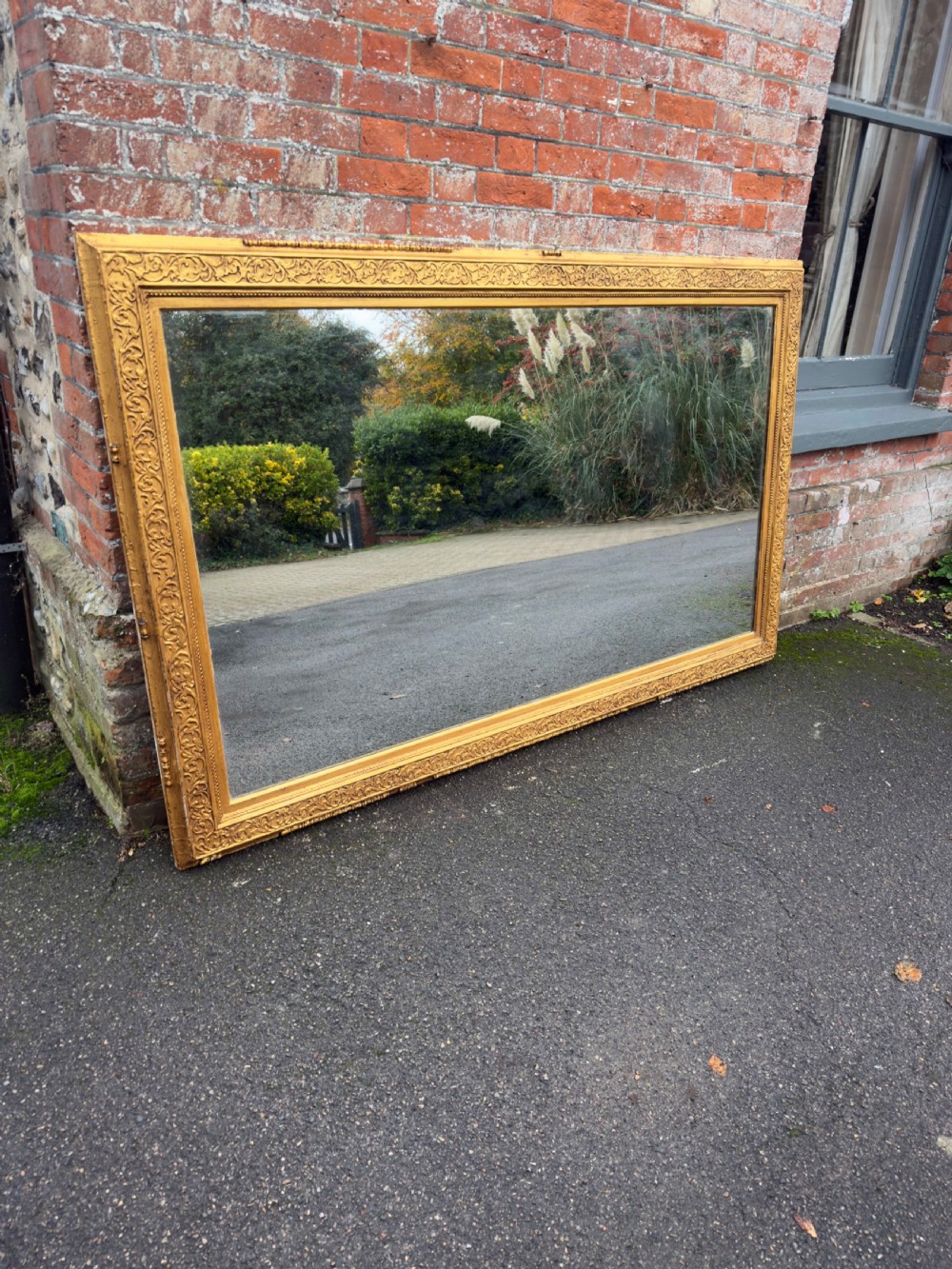 A large rectangular 19th-century English giltwood wall mirror featuring an ornate carved gesso frame with foliate moulding and a gold leaf finish.
