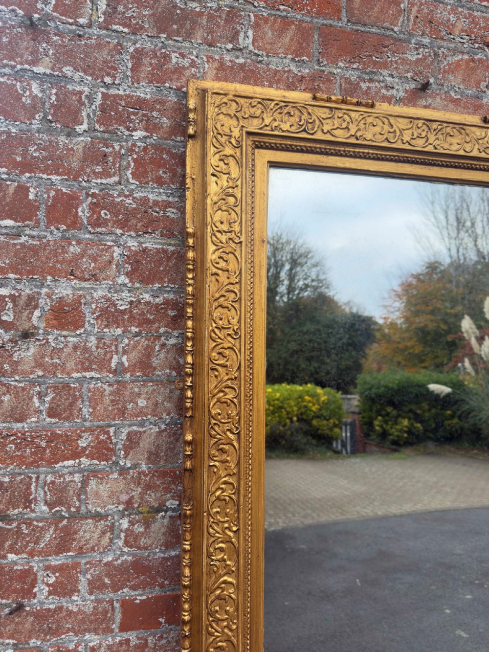 A large rectangular 19th-century English giltwood wall mirror featuring an ornate carved gesso frame with foliate moulding and a gold leaf finish. View VI