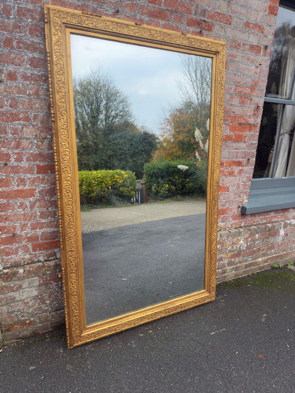 A large rectangular 19th-century English giltwood wall mirror featuring an ornate carved gesso frame with foliate moulding and a gold leaf finish. View VII