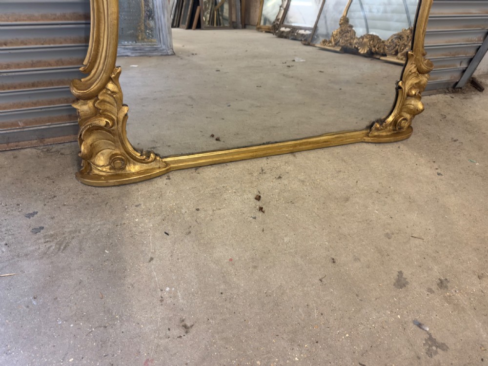 A large 19th-century giltwood overmantel mirror with an ornate carved cartouche crest and acanthus leaf scroll moulding. View II