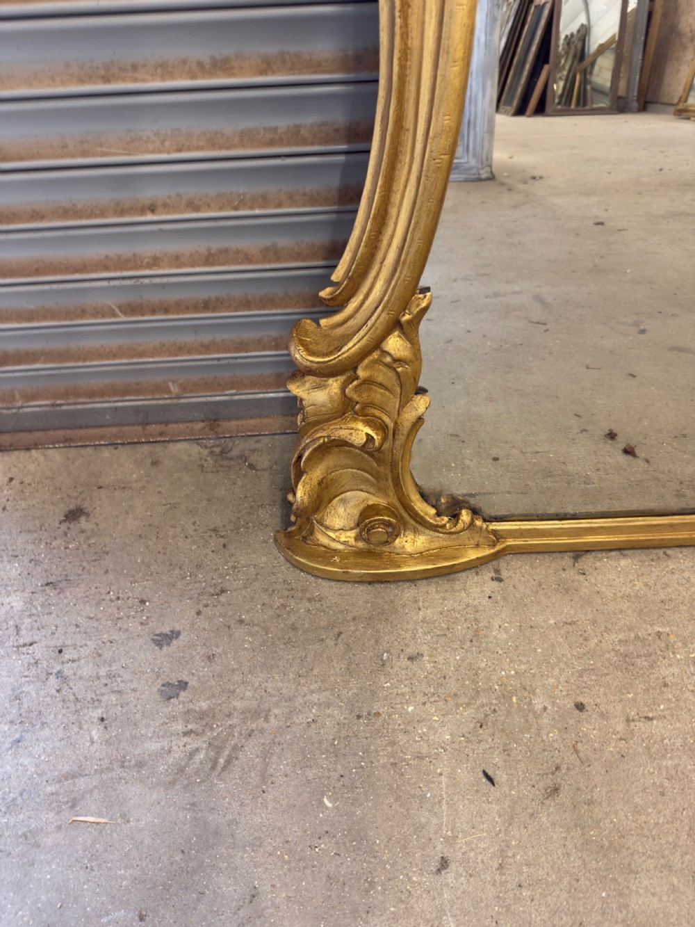 A large 19th-century giltwood overmantel mirror with an ornate carved cartouche crest and acanthus leaf scroll moulding. View IV
