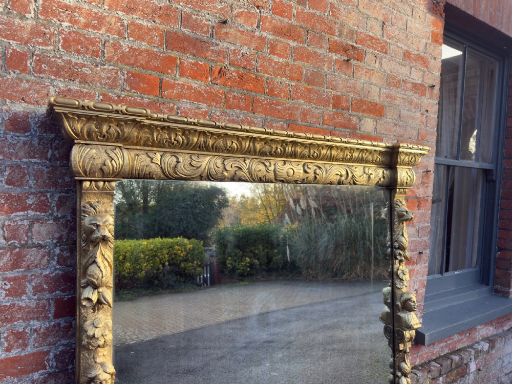 A large 19th-century rectangular giltwood overmantel mirror featuring detailed botanical scrollwork carvings and classical figural busts. View II