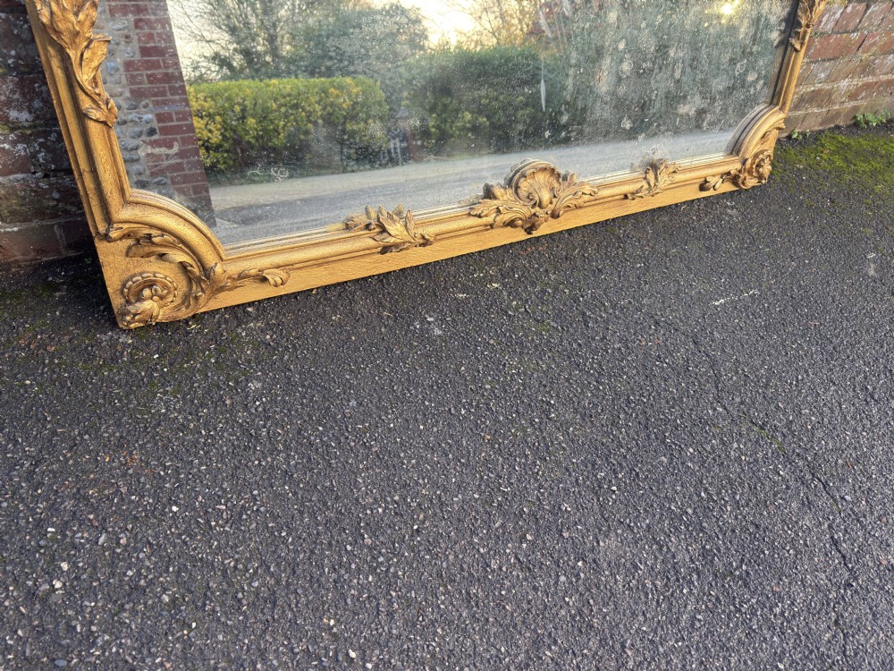 A large horizontal 19th-century overmantel mirror featuring a gilded wood and gesso frame with ornate carved acanthus leaf motifs. View IV