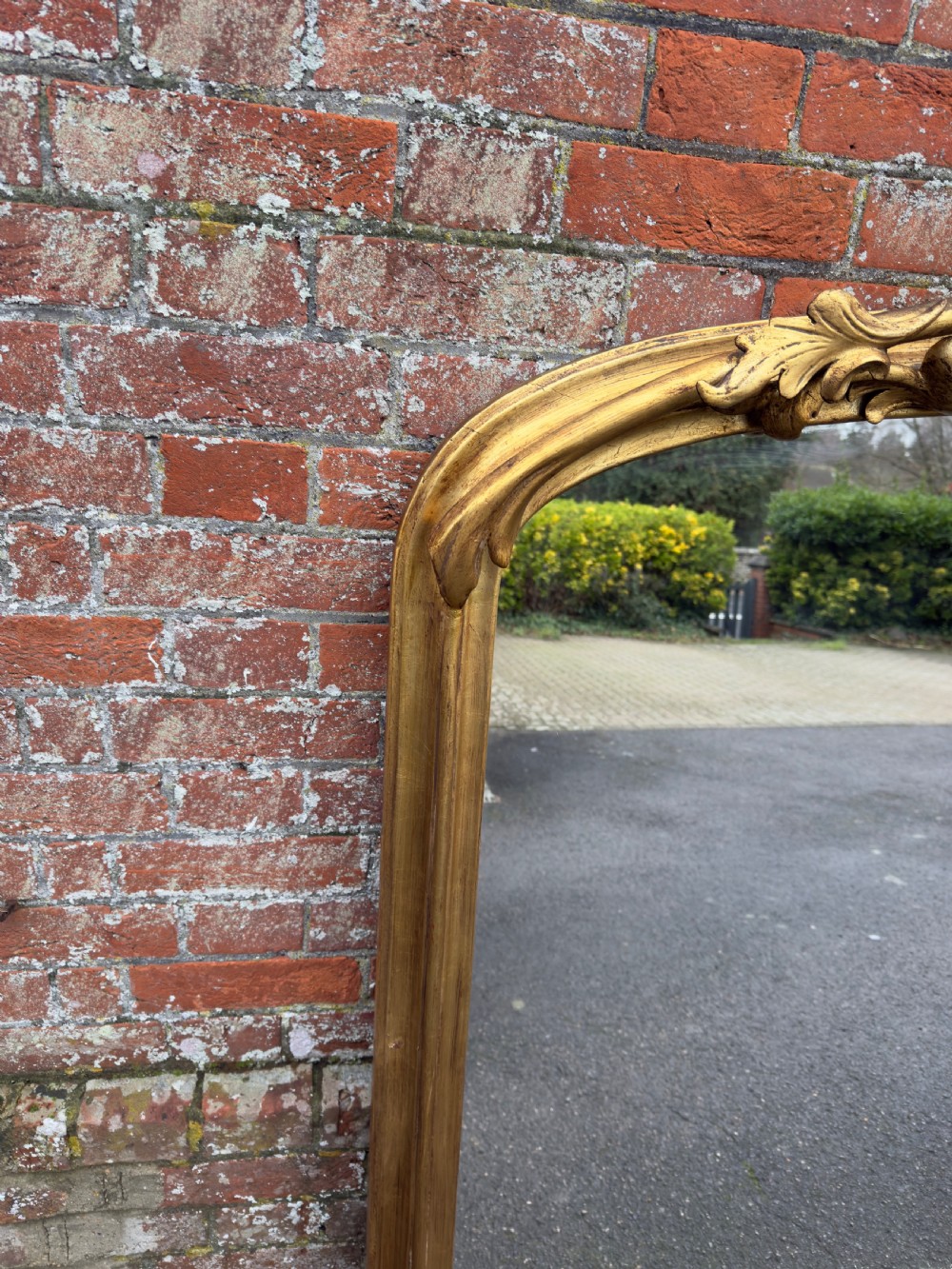 A large 19th-century giltwood overmantel mirror featuring an arched top adorned with a carved scroll and leaf cresting. View III