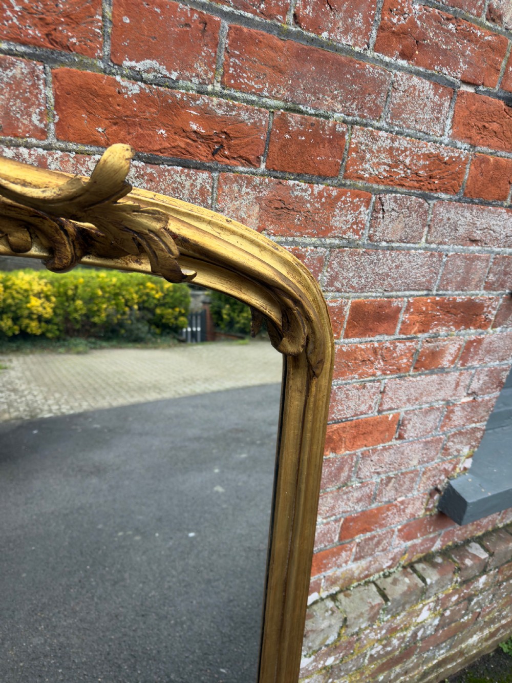 A large 19th-century giltwood overmantel mirror featuring an arched top adorned with a carved scroll and leaf cresting. View IV
