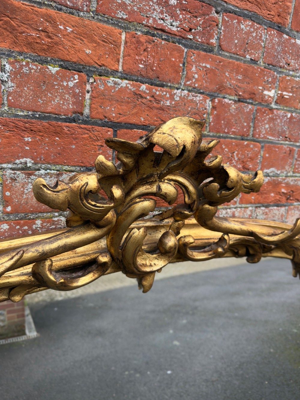 A large 19th-century giltwood overmantel mirror featuring an arched top adorned with a carved scroll and leaf cresting. View VI