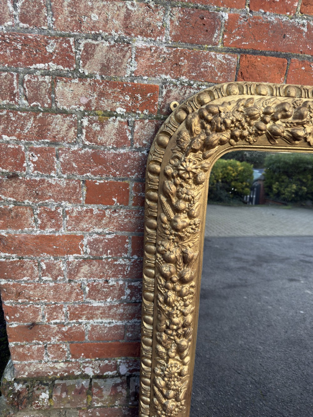 A large nineteenth-century Victorian giltwood and gesso overmantel mirror featuring an arched upper frame embellished with dense floral and fruit relief carvings. View V