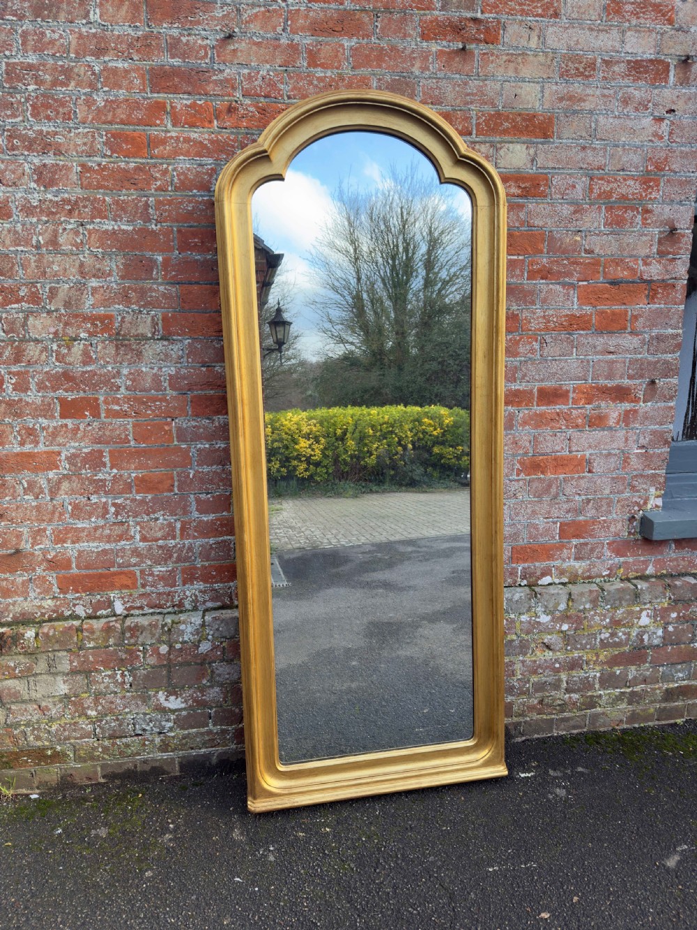 A tall 19th-century giltwood full-length mirror featuring a shaped arched top and continuous moulded frame.