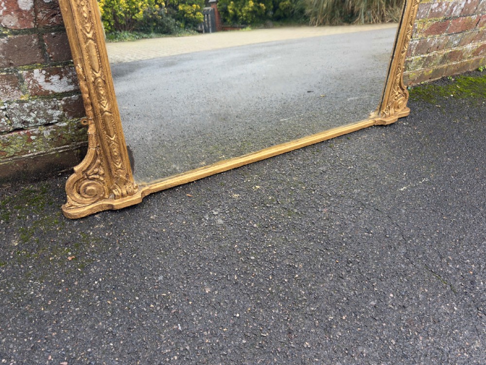 A large 19th-century rectangular overmantel mirror featuring a gilded gesso frame with floral moulding, scrolled side feet, and a stepped top cornice. View III