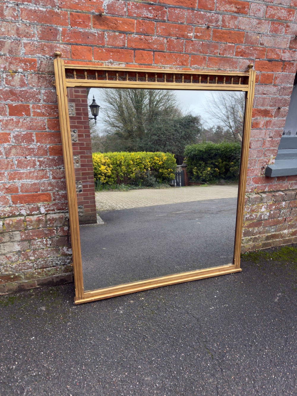 A large 19th-century rectangular gilt wood overmantel mirror featuring a upper spindle gallery and corner finials.