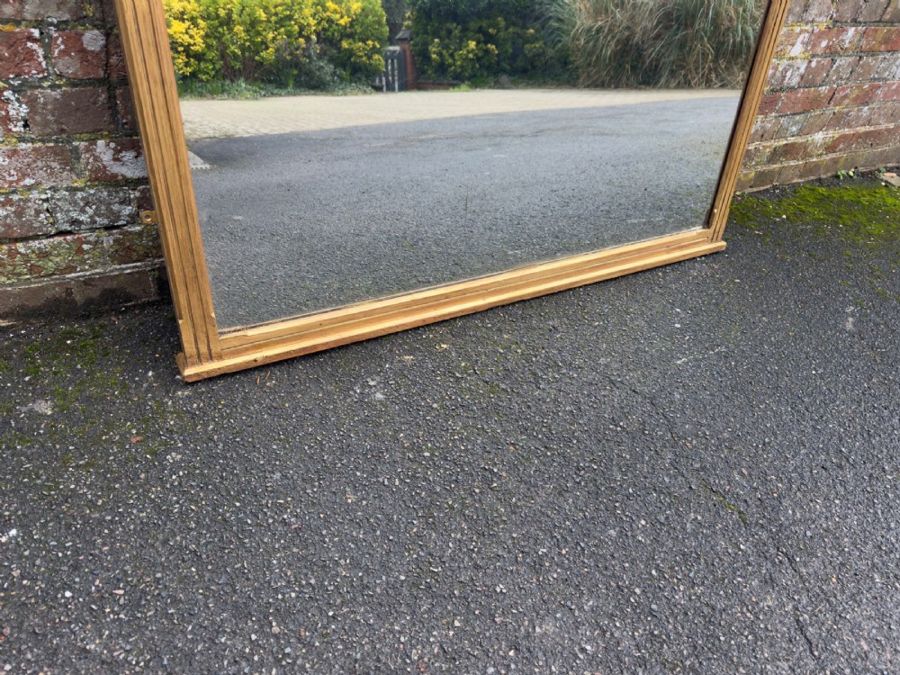 A large 19th-century rectangular gilt wood overmantel mirror featuring a upper spindle gallery and corner finials. View IV