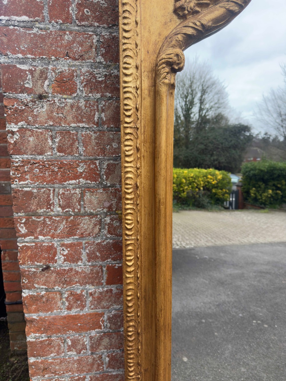 A large 19th-century English giltwood wall mirror with a shaped arched top and carved gesso detail. View II