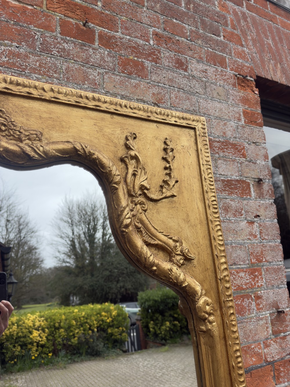 A large 19th-century English giltwood wall mirror with a shaped arched top and carved gesso detail. View IV