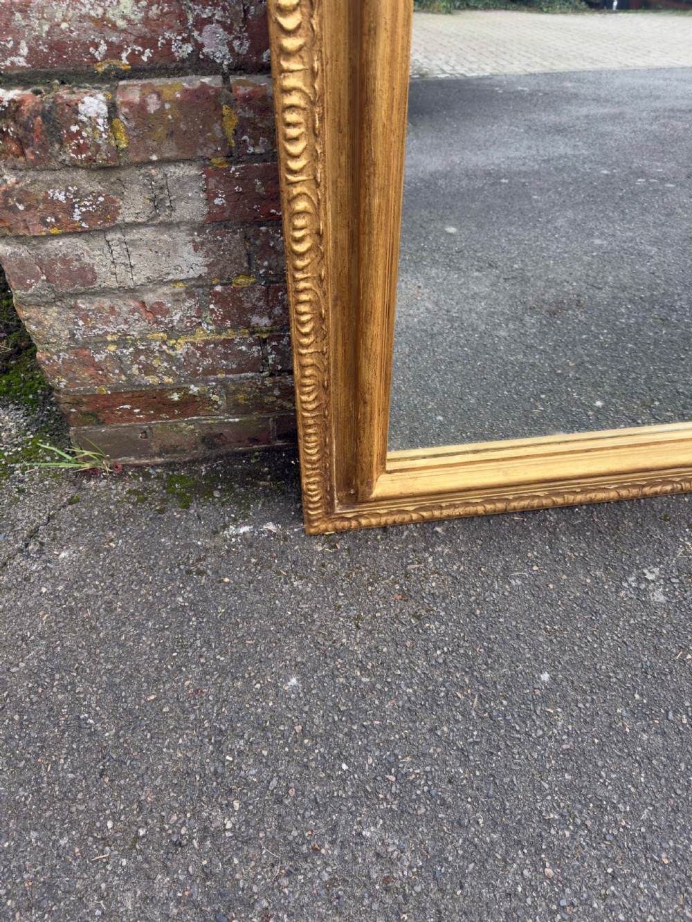 A large 19th-century English giltwood wall mirror with a shaped arched top and carved gesso detail. View VI