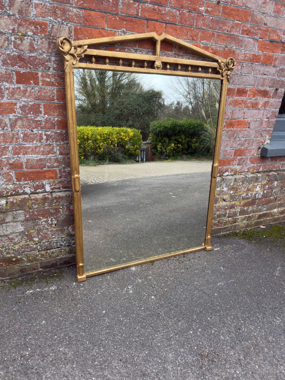 A large 19th-century rectangular giltwood overmantel mirror featuring a carved pediment with spindle detailing and foliate corner ornamentation.