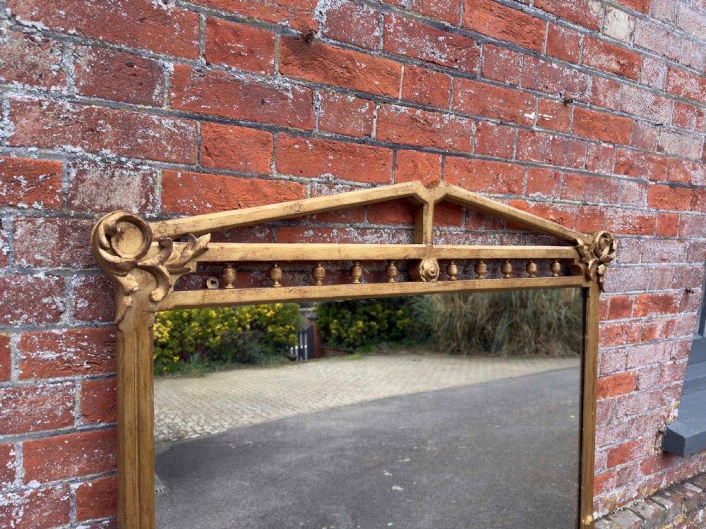 A large 19th-century rectangular giltwood overmantel mirror featuring a carved pediment with spindle detailing and foliate corner ornamentation. View II