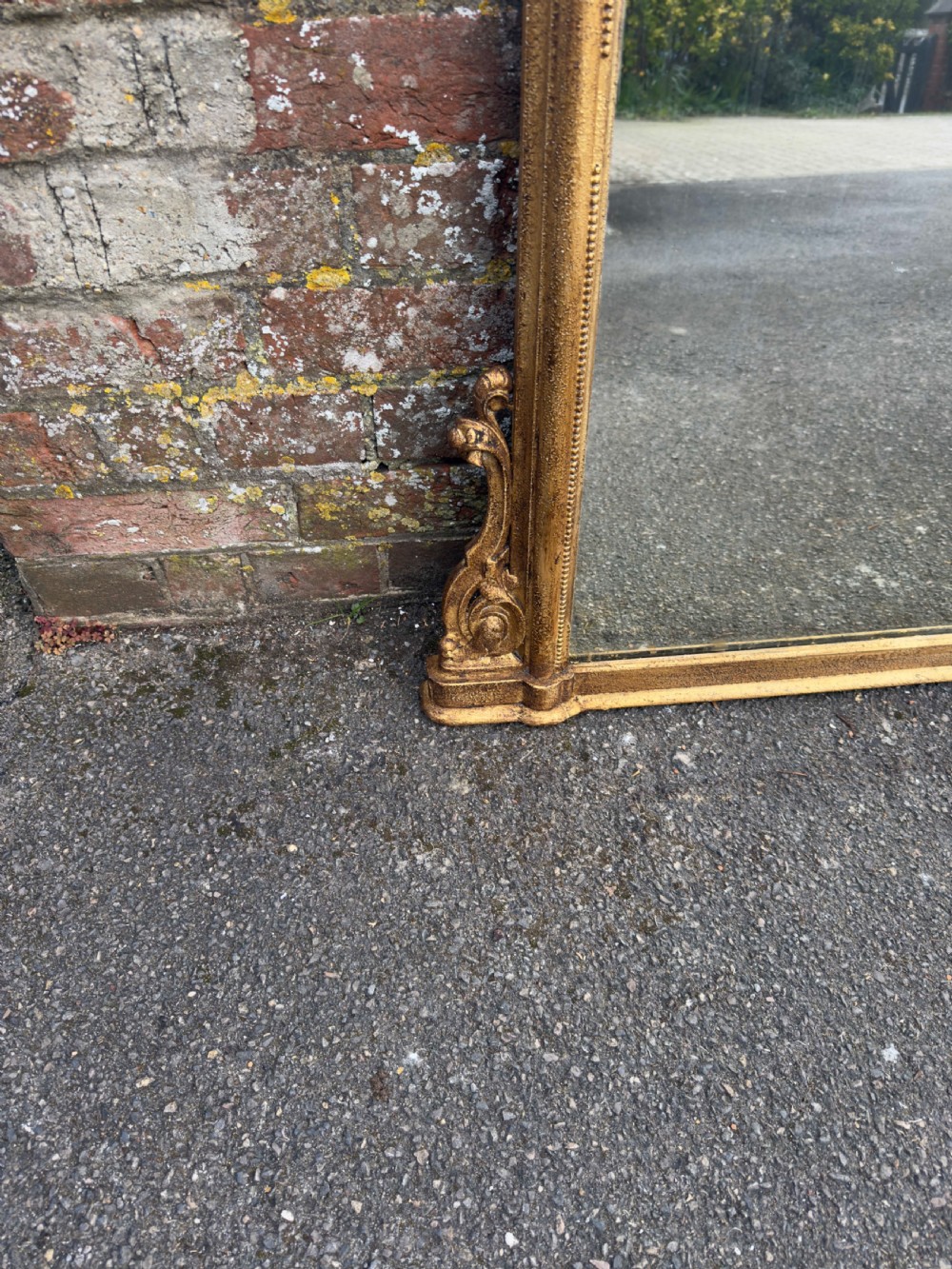 A large 19th-century English giltwood overmantel mirror featuring an arched top frame decorated with beaded moulding and carved scrollwork details at the base. View III